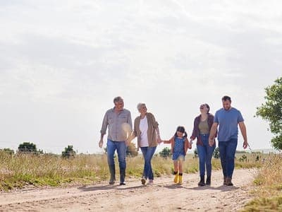 Happy multi-generational family walks through a field