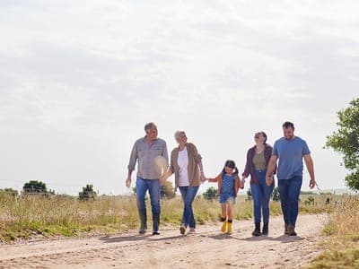 Happy multi-generational family walks through a field