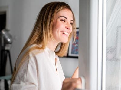 Plastic surgery patient smiles looking out window after healing from treatment